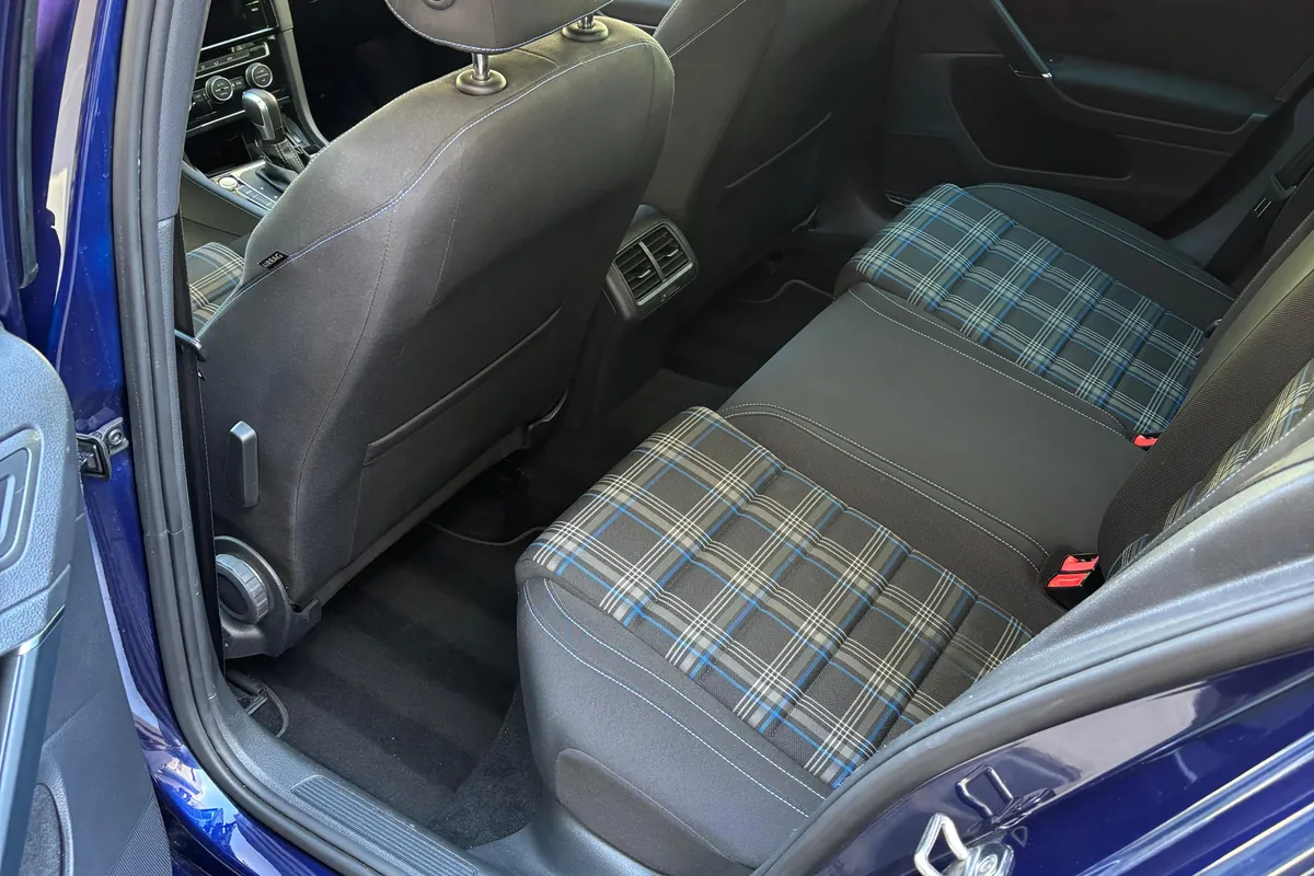 Asientos traseros de tela de cuadros de un Volkswagen Golf GTE azul, limpios y aspirados, con la puerta abierta