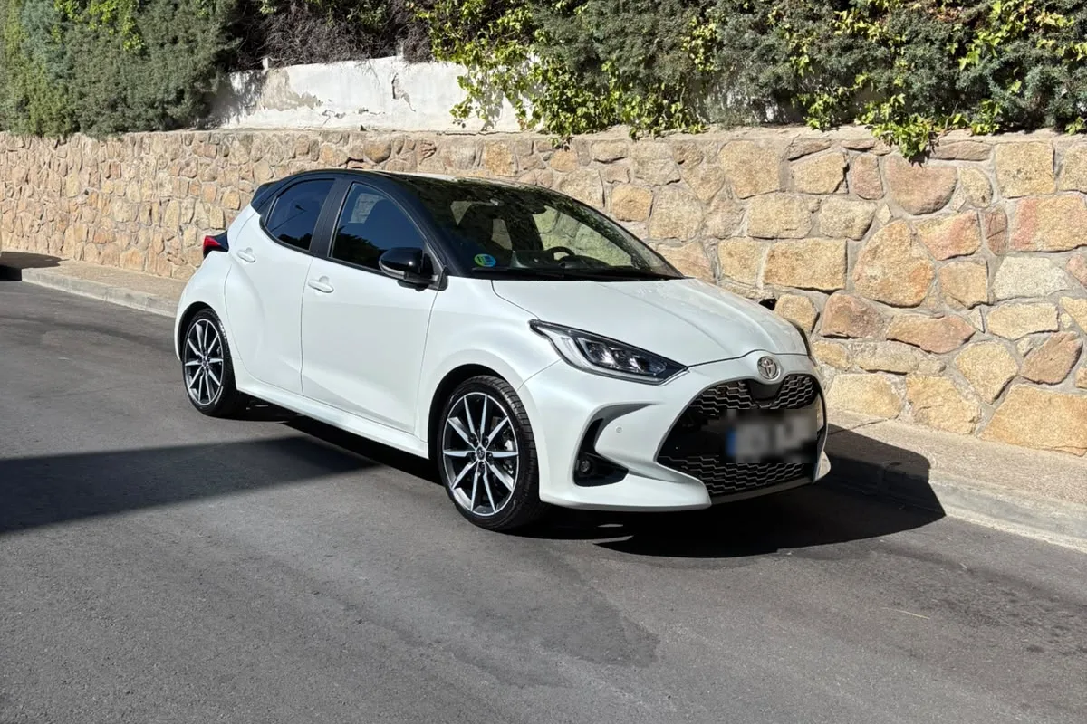 Toyota Yaris blanco recién salido de su tratamiento cerámico a domicilio, aparcado junto a un muro de piedra